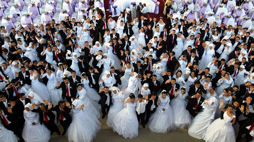 Brides and bridegrooms wave on the stage as they wait for their wedding ceremony in Ankara, August 6, 2006. 206 couples married together with an annual ceremony organised by Ankara municipality. REUTERS/Umit Bektas  (TURKEY) - RTR1G5LY