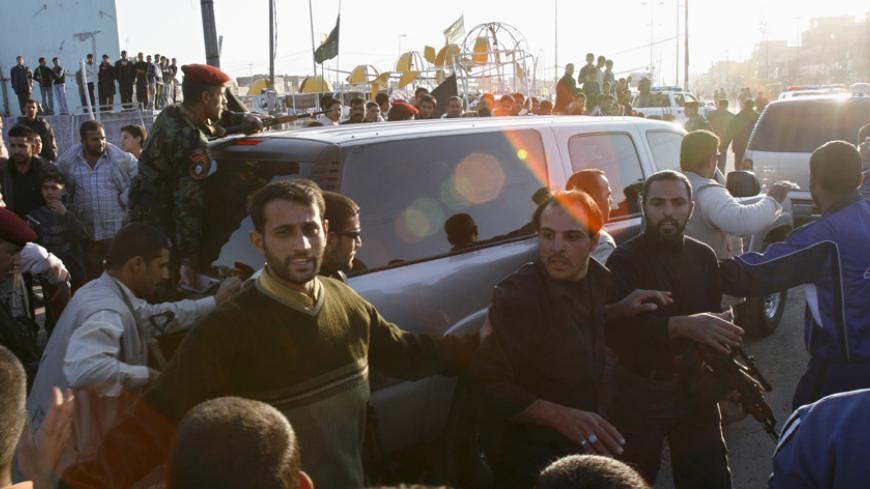 Security personnel surround the vehicle of Prime Minister Nuri al-Maliki as it leaves Baghdad's Sadr city November 26, 2006. Angry fellow Shi'ites threw rocks at Maliki's motorcade during his visit on Sunday to pay his respects to some of the 202 victims of last week's devastating bombing.    REUTERS/Mohammed Ameen  (IRAQ) - RTR1JQ7U