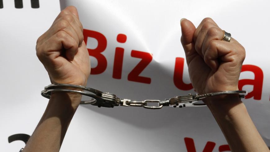 A woman raises her handcuffed hands during a protest in Ankara April 14, 2011. A group of female activists gathered to protest against the murder of women and abuse of children, and demanded state protection for those who face domestic violence. The partly seen banner reads: "We feel humiliated. What about you?" REUTERS/Umit Bektas (TURKEY - Tags: CIVIL UNREST SOCIETY) - RTR2L7HN