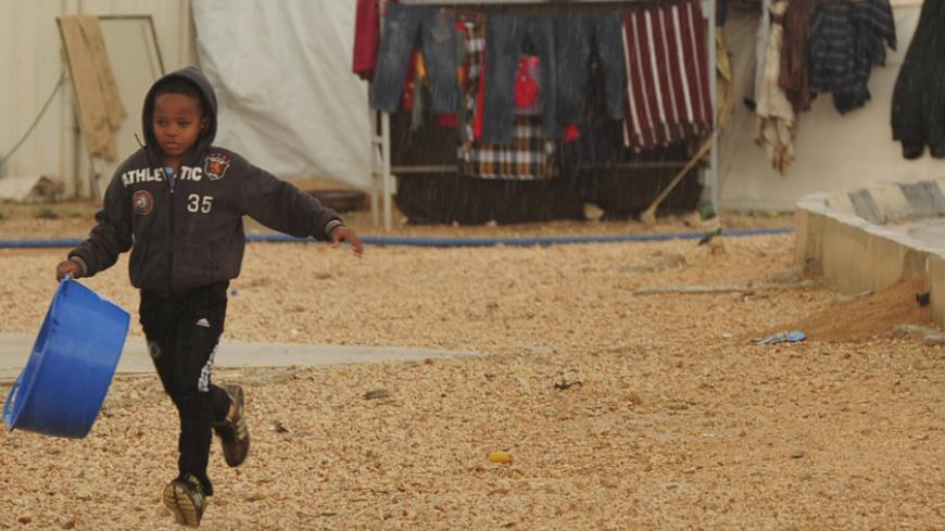 A child from the town of Tawargha runs in the rain in a refugee camp in Benghazi January 11, 2012. The Tawargha residents, who are waiting to return to their town after reprisals from anti-Gaddafi loyalists after the revolution, say that conditions in the camp are harsh and that their children have not been able to go to school in the new year.     REUTERS/Esam Al-Fetori   (LIBYA - Tags: POLITICS CIVIL UNREST SOCIETY) - RTR2W5I6