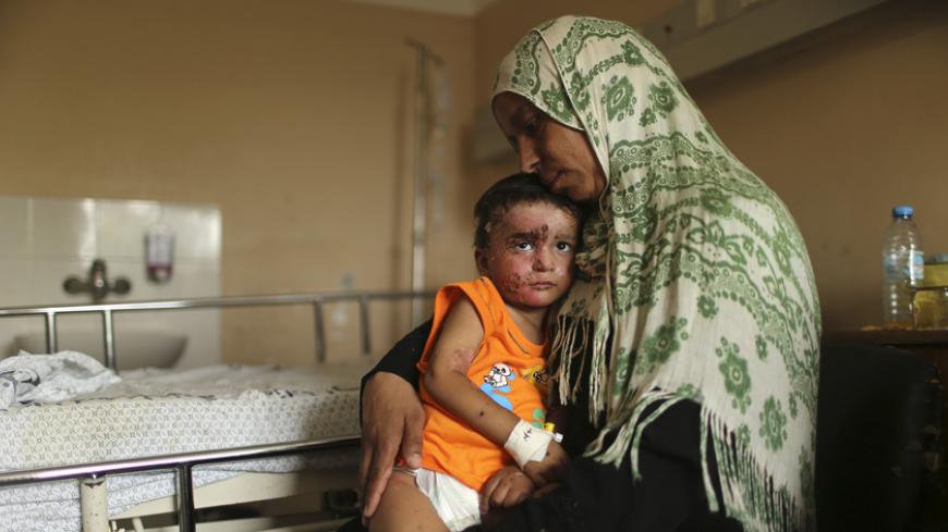 Palestinian boy Mohammed Wahdan, whom medics said was wounded in Israeli shelling, is held by his aunt as he receives psychological care at Shifa hospital in Gaza City August 14, 2014. In a ward at Shifa, Gaza's largest hospital, child therapist Rabeea Hamouda is trying to elicit a response from two small brothers, Omar and Mohammed, aged three and 18 months, hoping for some words or perhaps a smile. For seven straight minutes the children, peppered with burns and shrapnel wounds sustained in Israeli shelli