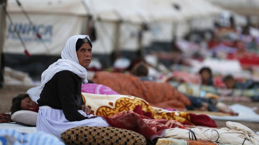 A woman looks on as she sits amongst displaced people from the minority Yazidi sect, who fled violence in the Iraqi town of Sinjar, who are sleeping on the ground at Bajed Kadal refugee camp, southwest of Dohuk province August 23, 2014. REUTERS/Youssef Boudlal (IRAQ - Tags: CIVIL UNREST POLITICS CONFLICT) - RTR43FCQ