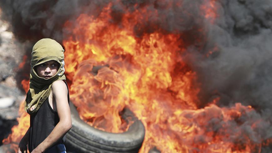 A Palestinian boy looks on near burning tyres during cashes with Israeli soldiers following a protest against the near-by Jewish settlement of Qadomem, in the West Bank village of Kofr Qadom near Nablus September 19, 2014. REUTERS/Abed Omar Qusini (WEST BANK - Tags: POLITICS CIVIL UNREST CONFLICT TPX IMAGES OF THE DAY) - RTR46XNM