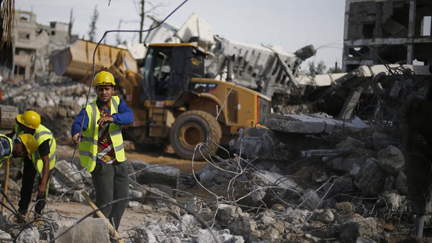 Palestinian workers participate in efforts to clear the rubble of a school, that witnesses said was destroyed by Israeli shelling during the most recent conflict between Israel and Hamas, in the east of Gaza City, December 3, 2014. According to housing minister Mufeed al-Hasayna, Gaza needs 8,000 tonnes of cement a day to meet demand. A new system set up with the United Nations to comply with Israeli requirements lets through at most 2,000, he said. At that rate, reconstruction would take more than 30 years