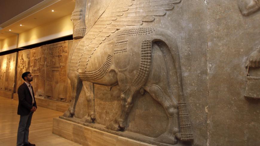 A man looks at ancient Assyrian human-headed winged bull statues at the Iraqi National Museum in Baghdad February 28, 2015. REUTERS/Khalid al-Mousily (IRAQ - Tags: POLITICS) - RTR4RIZ3