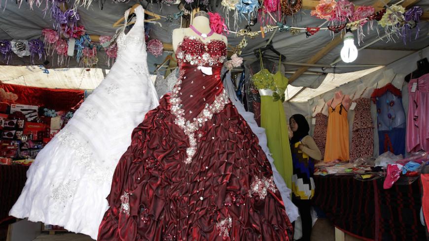 TO GO WITH AFP STORY BY KAMAL TAHA 
A woman  looks at dresses in a covered stall in the northern Jordanian Zaatari refugee camp, now home to 160,000 Syrians, equal in size to what would be Jordan's fifth-largest city, on May 18, 2013. With no end in sight to Syria's conflict, some refugees in Jordan are offering their daughters for early marriage in the hope of securing them protection as they face growing economic pressure. AFP PHOTO/KHALIL MAZRAAWI        (Photo credit should read KHALIL MAZRAAWI/AFP/Gett