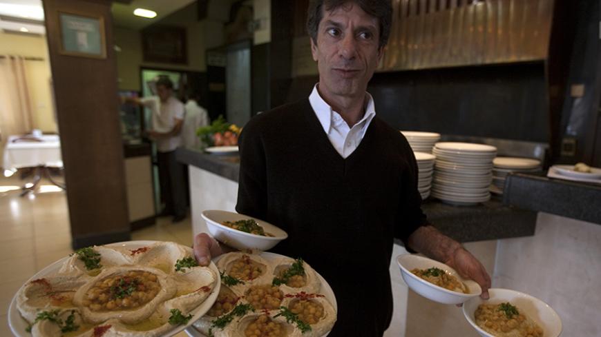 TO GO WITH AFP STORY BY PATRICK MOSER 
Israeli Arab waiter Majed Ibrahim carries various types of hummus dishes at a restaurant in the town of Abu Gosh near Jerusalem on January 4, 2010. At the risk of whipping up discord with Lebanon, the Arab-Israeli village is planning to make the world's biggest hummus, a humble chickpea dip that stirs passions across the Middle East. AFP PHOTO/Menahem KAHANA (Photo credit should read MENAHEM KAHANA/AFP/Getty Images)