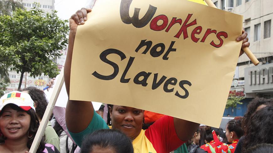 A migrant domestic worker holds up a placard during a parade in Beirut, to support the rights of migrant domestic workers in Lebanon, ahead of May Day, April 29, 2012. The domestic worker industry in Lebanon is vast - foreign maids account for more than five percent of the population - and the sector is plagued by archaic labour laws, inhumane practices and dire wages. REUTERS/ Mohamed Azakir (LEBANON - Tags: CIVIL UNREST BUSINESS EMPLOYMENT POLITICS) - RTR31DDR