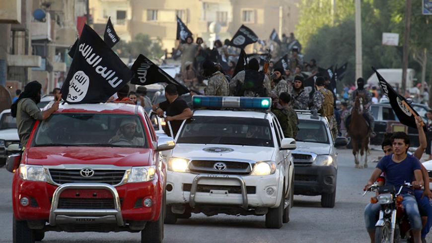 Militant Islamist fighters waving flags, travel in vehicles as they take part in a military parade along the streets of Syria's northern Raqqa province June 30, 2014. The fighters held the parade to celebrate their declaration of an Islamic "caliphate" after the group captured territory in neighbouring Iraq, a monitoring service said. The Islamic State, an al Qaeda offshoot previously known as Islamic State in Iraq and the Levant (ISIL), posted pictures online on Sunday of people waving black flags from car