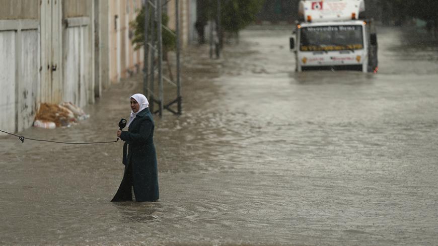 A Palestinian journalist speaks to the camera as she stands on a flooded street following heavy rain in Gaza City November 27, 2014. The civil defence asked residents in an area east of Gaza City to evacuate their homes to avoid being trapped in flood waters from a nearby lake. REUTERS/Mohammed Salem (GAZA - Tags: SOCIETY ENVIRONMENT MEDIA TPX IMAGES OF THE DAY) - RTR4FST8