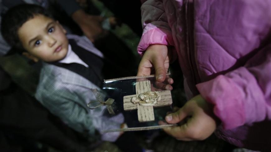 An Iraqi Christian refugee girl holds a souvenir of the Holy Family as a boy looks on at a church in Hazmiyeh, near Beirut December 12, 2014. Christian leaders led the service for around 600 Iraqi Christian refugees, many of them children and the elderly. Iraqi Christians who sought refuge in Lebanon after Islamist militants tore through their homeland said they had no idea when they would be able to return as they gathered for prayers ahead of Christmas. Picture taken December 12, 2014. REUTERS/Jamal Saidi