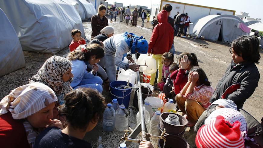 Kurdish refugees from the Syrian town of Kobani wait to fill their bottles around a clean water source at a refugee camp in the border town of Suruc, Sanliurfa province, February 1, 2015. REUTERS/Umit Bektas (TURKEY - Tags: POLITICS CIVIL UNREST CONFLICT) - RTR4NRTZ