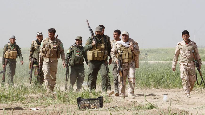 Shi'ite fighters from Hashid Shaabi forces walk with their weapons at the front line at the Shi'ite Turkman village of Bashir, 20km south of Kirkuk, March 14, 2015. Kurdish peshmerga forces, backed by Shi'ite militia fighters, have been attacking Islamic State-held towns and villages south and west of the oil-rich city of Kirkuk, peshmerga sources said. REUTERS/Ako Rasheed (IRAQ - Tags: CIVIL UNREST CONFLICT POLITICS MILITARY) - RTR4TCDN