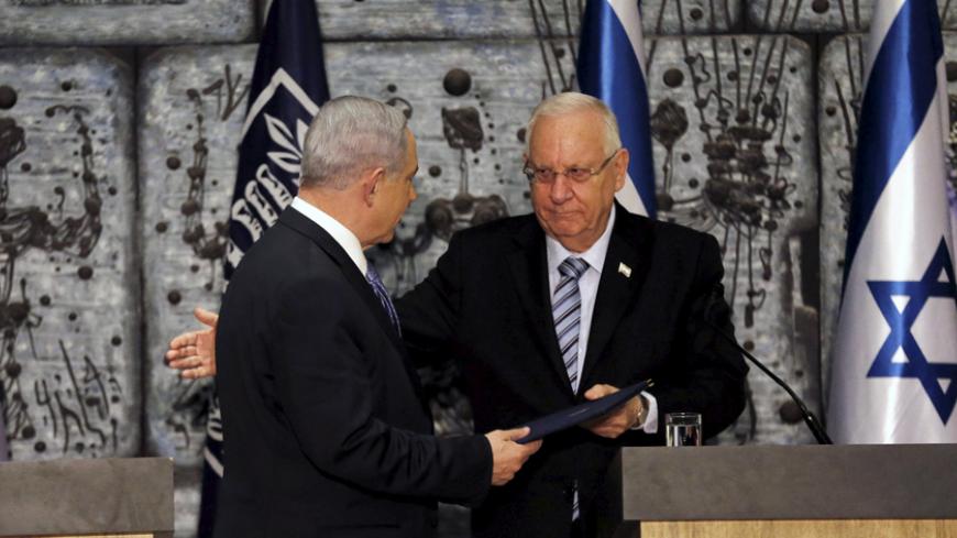 Israeli Prime Minister Benjamin Netanyahu (L) receives a folder from Israeli President Reuven Rivlin during a ceremony in Jerusalem March 25, 2015. Netanyahu, grappling with fierce White House disapproval, won consent from Israel's president on Wednesday to try to form a new coalition government. REUTERS/Ammar Awad - RTR4UVGJ
