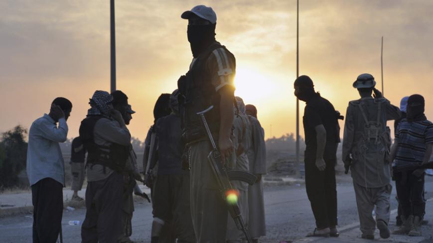 Fighters of the Islamic State of Iraq and the Levant (ISIL) stand guard at a checkpoint in the northern Iraq city of Mosul, June 11, 2014. Since Tuesday, black clad ISIL fighters have seized Iraq's second biggest city Mosul and Tikrit, home town of former dictator Saddam Hussein, as well as other towns and cities north of Baghdad. They continued their lightning advance on Thursday, moving into towns just an hour's drive from the capital. Picture taken June 11, 2014. REUTERS/Stringer (IRAQ - Tags: CIVIL UNRE