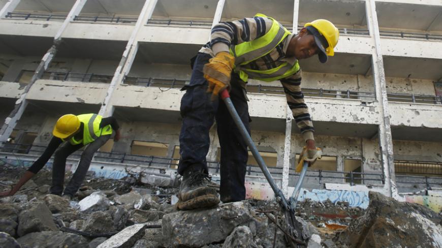 Palestinian workers clear the rubble of a school that witnesses said was destroyed by Israeli shelling during the most recent conflict between Israel and Hamas, in the east of Gaza City December 3, 2014. According to housing minister Mufeed al-Hasayna, Gaza needs 8,000 tonnes of cement a day to meet demand. A new system set up with the United Nations to comply with Israeli requirements lets through at most 2,000, he said. At that rate, reconstruction would take more than 30 years, said Hasayna, one of four