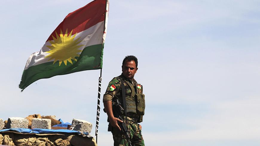 A Kurdish flag is seen as a member of the Kurdish Peshmerga forces stands guard at a security point on Bashiqa mountain, overlooking Islamic State held territories of Mosul, 12 km northeast of Mosul City, March 7, 2015.  REUTERS/Asmaa Waguih (IRAQ - Tags: POLITICS MILITARY CONFLICT TPX IMAGES OF THE DAY) - RTR4SF4S