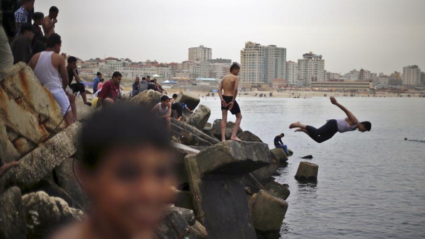 A Palestinian boy jumps into the Mediterranean Sea as he enjoys a warm day with others at the seaport of Gaza City March 27, 2015. REUTERS/Mohammed Salem