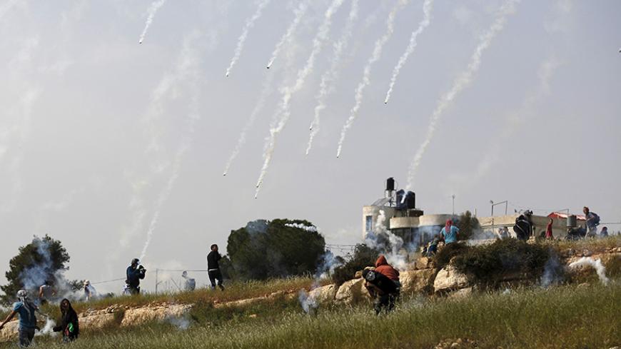 Palestinian protesters run from tear gas canisters launched by Israeli troops during clashes following a protest marking the Land Day, in the West Bank village of Nabi Saleh near Ramallah March 28, 2015. Palestinians marks Land Day on March 30, the annual commemoration of protests in 1976 against Israel's appropriation of Arab-owned land in the Galilee. REUTERS/Mohamad Torokman      TPX IMAGES OF THE DAY      - RTR4V9NG