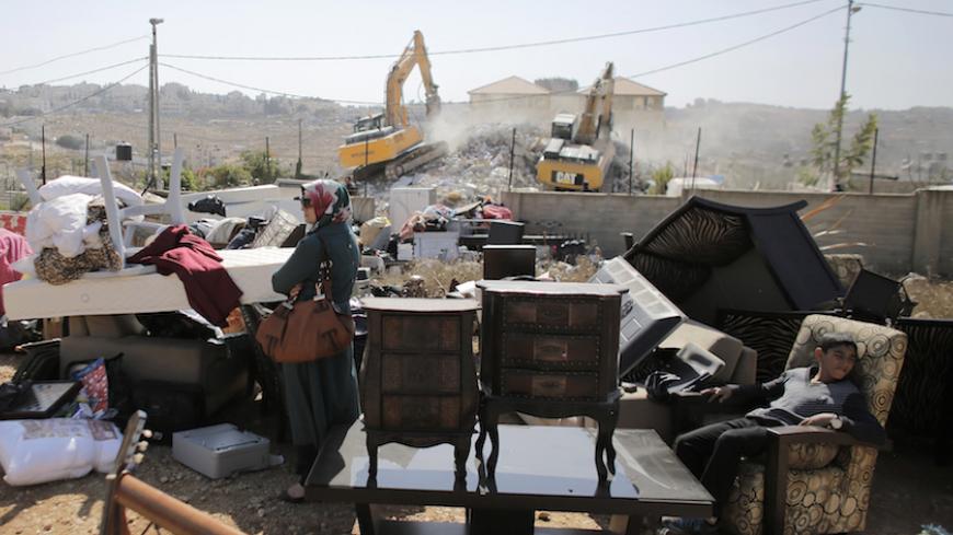A Palestinian woman stands near furniture removed from her house as it is being demolished in the East Jerusalem neighbourhood of Beit Hanina October 29, 2013. A statement from the Jerusalem Municipality said there was a court order for the demolition of the house, which was built without a permit. REUTERS/Ammar Awad (JERUSALEM - Tags: POLITICS BUSINESS CONSTRUCTION TPX IMAGES OF THE DAY) - RTX14SGK