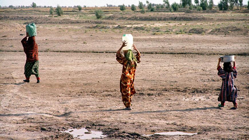 Young Iranian women carry jugs of water, filled at water distribution point, to their village outside Zabol in south eastern Iran, July 17, 2001. Iran's Sistan-Baluchistan province is suffering from a third consecutive year of drought which the United Nations says has cost the country $2.6 billion in dammages this year, up from $1.7 billion last year. Local officials say without rain remaining water sources will dry up by December. - RTXKN5I