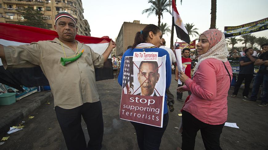 An Egyptian woman puts turns her back to show an image of US President Barack Obama with a slogan, as they rally in Cairo's Tahrir Square, on July 7, 2013. Opponents of Egypt's deposed Islamist president Mohamed Morsi packed Tahrir Square in their tens of thousands to show the world his ouster was not a military coup but the reflection of the people's will. AFP PHOTO / KHALED DESOUKI (Photo credit should read KHALED DESOUKI/AFP/Getty Images)
