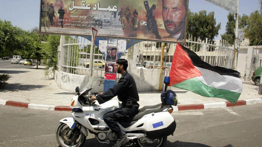 A Hamas policeman rides a motorcycle past a billboard promoting a film titled "Imad Aqel" in Gaza City August 3, 2009. "Imad Aqel", which had its premiere on Saturday, is the first feature film produced by the Islamist Hamas movement and the title is the name of a Palestinian militant whom Israel held accountable for the deaths of 13 soldiers and settlers. REUTERS/Ismail Zaydah (GAZA POLITICS SOCIETY ENTERTAINMENT) - RTR26DLS