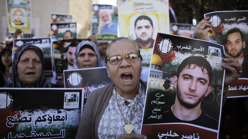 Palestinian protesters hold placards depicting their relatives during a demonstration to show their solidarity with hunger-striking Palestinian prisoners held by Israel, outside the Red Cross building in Jerusalem June 12, 2014. Some 70 protesters took part in the demonstration on Thursday. Hundreds of Palestinian prisoners in Israeli jails have joined a hunger strike since late April, in protest over an Israeli policy allowing indefinite detention without trial. REUTERS/Ammar Awad (JERUSALEM - Tags: POLITI