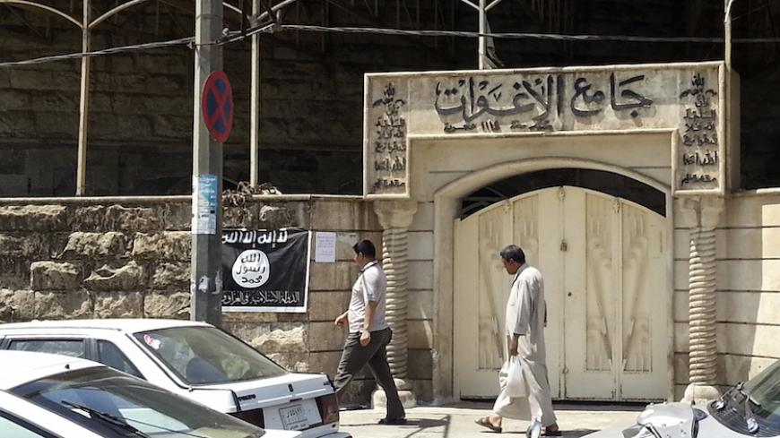 People walk past a banner (in black and white) belonging to the Islamic State in Iraq and the Levant (ISIL) in the city of Mosul, June 28, 2014. Since early June, ISIL militants have overrun most majority Sunni Muslim areas in the north and west of Iraq, capturing the biggest northern city Mosul and late dictator Saddam Hussein's hometown of Tikrit. The banner reads, "There is no God but God, and Mohammad is his messenger." REUTERS/Stringer (IRAQ - Tags: CIVIL UNREST POLITICS) - RTR3W71S