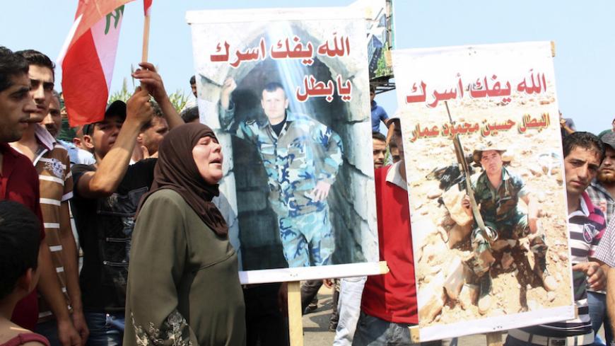 Relatives of Lebanese soldiers, who were captured by Islamist militants in Arsal, carry pictures of two of them during a protest demanding their release and pressuring the government to act, as they blocked a main road linking Tripoli to Halba, in al-Mhmara town, northern Lebanon August 30, 2014. Islamic State militants beheaded a Lebanese soldier who was one of 19 captured by hardline Syrian Islamists when they seized a Lebanese border town for few days this month, a video posted on social media showed on 