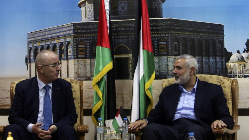 Senior Hamas leader Ismail Haniyeh (R) speaks with Palestinian Prime Minister Rami Hamdallah at Haniyeh's house in Gaza City October 9, 2014. Hamdallah arrived in the Hamas-dominated Gaza Strip on Thursday and convened the first meeting of a unity government there since a brief civil war in 2007 between Hamas and forces loyal to the Fatah party. REUTERS/Ibraheem Abu Mustafa (GAZA - Tags: POLITICS CIVIL UNREST) - RTR49J6X