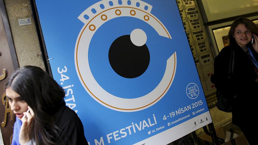 People speak on their mobile phones next to a banner of Istanbul Film Festival at the entrance of Atlas movie theatre in Istanbul April 14, 2015. Nearly two dozen filmmakers and a group of international critics have pulled out of the Istanbul Film Festival after the government prevented the screening of a film about Kurdish militants, in the latest outcry over censorship in Turkey. At least 22 films from the roughly 200 submitted were withdrawn this week and the festival competition cancelled, according to 