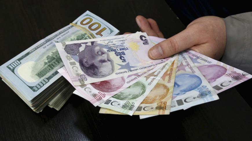 A money changer holds Turkish lira banknotes next to U.S. dollar bills at a currency exchange office in central Istanbul April 15, 2015. Turkish Economy Minister Nihat Zeybekci said on Wednesday the lira's slide to record lows was not a cause for concern and reflected global developments, arguing against forex intervention and saying the currency will find its own balance. He also told a meeting in Istanbul that he expected first quarter year-on-year growth of around 1.5 percent, and full year growth exceed