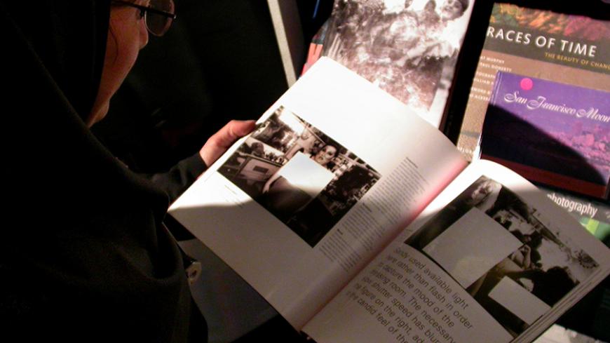 An young Iranian woman takes a look at a censored book at the 18th Tehran International Book Fair May 6, 2005. Iran's Culture Ministry ordered the Iranian representation of foreign publishers to censor all pictures that show a part or complete part of a woman or man's nude body. REUTERS/Morteza Nikoubazl  MN/JK/DH - RTRACIC