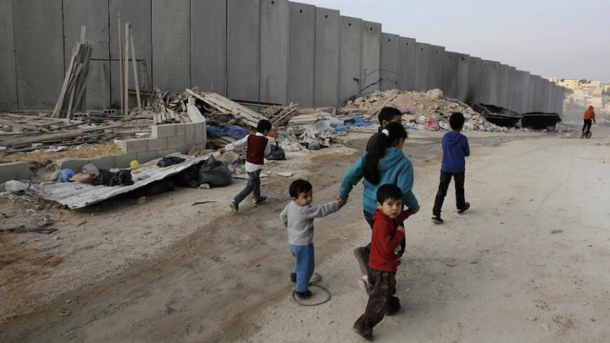 Palestinian children walk past garbage discarded near a section of the controversial Israeli barrier, in Shuafat refugee camp in the West Bank near Jerusalem November 21, 2013. Marooned behind the wall, Israel's controversial barrier, the Shuafat refugee camp reveals the state's uneven treatment of Arab and Jewish neighbourhoods, creating a de facto partition of Jerusalem, which is the epicentre of the Middle East conflict. Picture taken November 21, 2013. REUTERS/Ammar Awad (WEST BANK - Tags: POLITICS SOCI