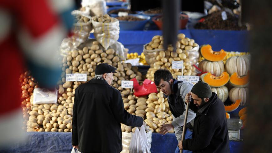 A vendor sells potatoes and other vegetables to a customer in an open market in central Ankara February 5, 2014. The humble potato has become a factor in Turkey's political and economic turmoil as prices of the staple soar, hurting the living standards of poorer Turks just before the ruling AK Party's toughest election test in a decade. At a market in the lower-income Istanbul suburb of Kucukcekmece, potatoes sell for between 3 and 4 lira ($1.33 and $1.77) a kilogramme, up from slightly more than 1 lira at 