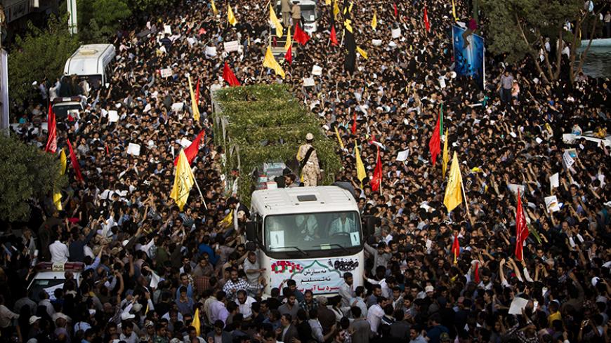 Iranians follow trucks carrying coffins towards Tehran's Baharestan square on June 16, 2015 during a funeral procession for 270 victims of the Iran-Iraq war (1980-1988) (175 of them belonging to a group of military divers), a month after their bodies were repatriated to Iran. The divers were responsible for breaking the enemy lines during an operation in 1986 with the aim of taking Basra in southern Iraq, but the operation was discovered by the Iraqi army that killed a large number of Iranian military and m