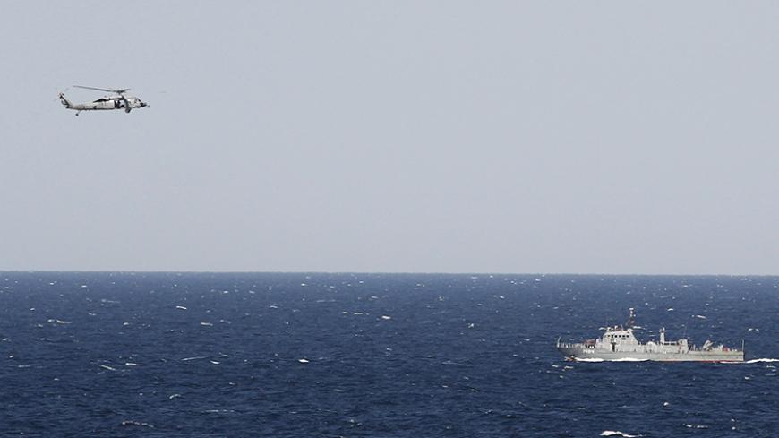 A helicopter from the Nimitz-class aircraft carrier USS Abraham Lincoln (CVN 72) hovers over an Iranian patrol ship during a transit through the Strait of Hormuz, February 14, 2012. REUTERS/Jumana El Heloueh (GULF - Tags: POLITICS MILITARY) - RTR2XU5R