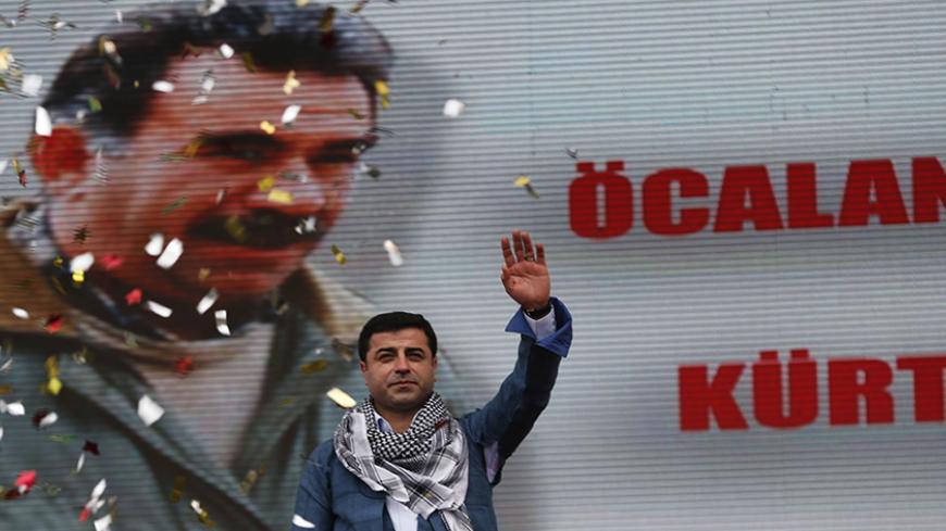 Selahattin Demirtas, co-chairman of the pro-Kurdish Peace and Democracy Party, greets his supporters during a rally to celebrate the spring festival of Newroz in Istanbul March 17, 2013. A picture of imprisoned PKK leader Abdullah Ocalan is seen in the background. REUTERS/Murad Sezer (TURKEY - Tags: POLITICS CIVIL UNREST) - RTR3F4BY