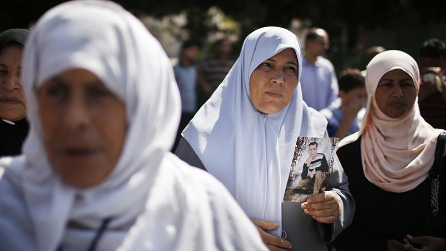 A Palestinian woman holds a picture of a jailed relative during a rally in solidarity with hunger-striking Palestinian prisoners held by Israel, in Gaza City June 11, 2014. Israel's parliament has given initial approval to a law to enable the force-feeding of Palestinian prisoners on a hunger strike, drawing defiance from activists who said on Tuesday it would not deter the inmates. REUTERS/Mohammed Salem (GAZA - Tags: POLITICS) - RTR3T6PC
