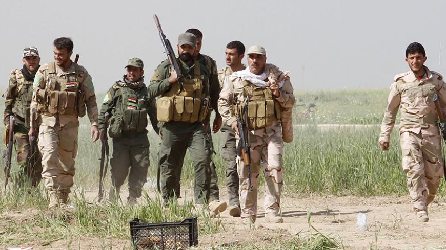 Shi'ite fighters from Hashid Shaabi forces walk with their weapons at the front line at the Shi'ite Turkman village of Bashir, 20km south of Kirkuk, March 14, 2015. Kurdish peshmerga forces, backed by Shi'ite militia fighters, have been attacking Islamic State-held towns and villages south and west of the oil-rich city of Kirkuk, peshmerga sources said. REUTERS/Ako Rasheed (IRAQ - Tags: CIVIL UNREST CONFLICT POLITICS MILITARY) - RTR4TCDN