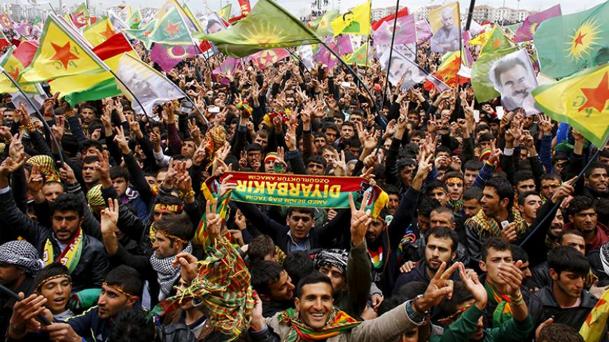 People gesture while others wave Kurdish flags during a gathering celebrating Newroz, which marks the arrival of spring and the new year, in Diyarbakir March 21, 2015. Jailed Kurdish rebel leader Abdullah Ocalan called on Saturday for his militant group to hold a congress on ending a three-decade insurgency against the Turkish state but stopped short of declaring an immediate halt to its armed struggle. Tens of thousands of Kurds gathered in the southeastern city of Diyarbakir to hear the message from Kurdi