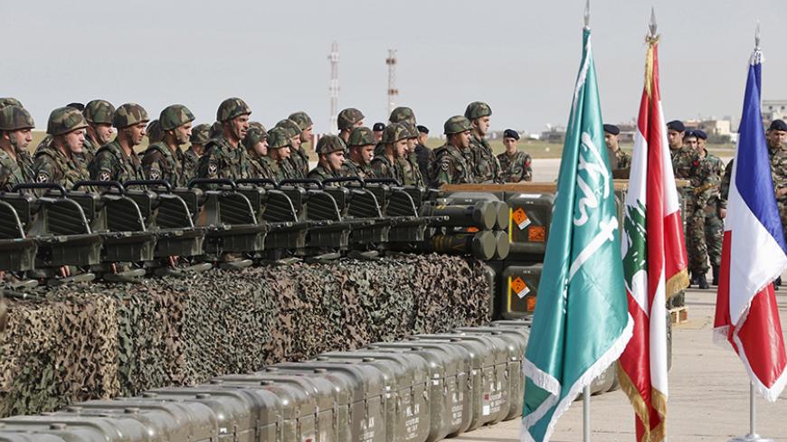 Lebanese army soldiers stand next to displayed weapons that they received during a ceremony at Beirut airport airbase April 20, 2015. The first shipment of French weapons and military equipment arrived in Lebanon on Monday under a Saudi-funded deal worth $3 billion to bolster the Lebanese army's fight against militants encroaching from neighboring Syria. (From L to R) The national flags of Saudi Arabia, Lebanon and France are displayed during the ceremony. REUTERS/Mohamed Azakir  - RTX19H2B