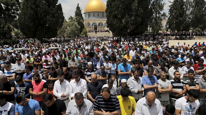 Palestinian men take part in Friday prayers as the Dome of the Rock on the compound known to Muslims as the Noble Sanctuary and to Jews as Temple Mount in Jerusalem's Old City is seen in the background May 29, 2015. Picture taken May 29, 2015. To match Special Report ISRAEL-JERUSALEM/DOME REUTERS/Ammar Awad
- RTX1F1V6