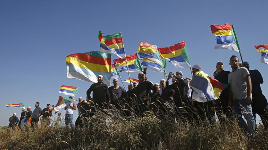 Members of the Druze community watch the fighting in the Druze village of Khadr in Syria, as they stand on the Israeli side of the border fence between Syria and the Israeli-occupied Golan Heights, near Majdal Shams, June 16, 2015. Israel's president expressed his concern to the United States last week about the fate of the Druze minority in Syria, saying around 500,000 of them were under threat from Islamist militants in an area near the Israeli border. REUTERS/Baz Ratner - RTX1GRM4