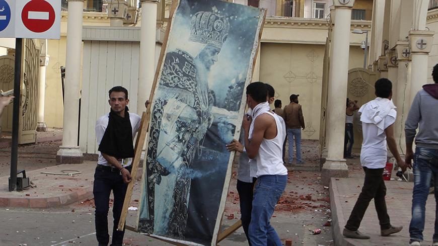 Coptic Christians remove a picture of Pope Shenoda III from the gate of the main cathedral in Cairo during clashes with Muslims standing outside the cathedral April 7, 2013. Clashes broke out between Coptic Christians and Muslims in central Cairo on Sunday after the funeral of four Copts killed in sectarian violence outside the Egyptian capital on Friday night, witnesses said.  REUTERS/Asmaa Waguih (EGYPT - Tags: RELIGION CIVIL UNREST) - RTXYC6T