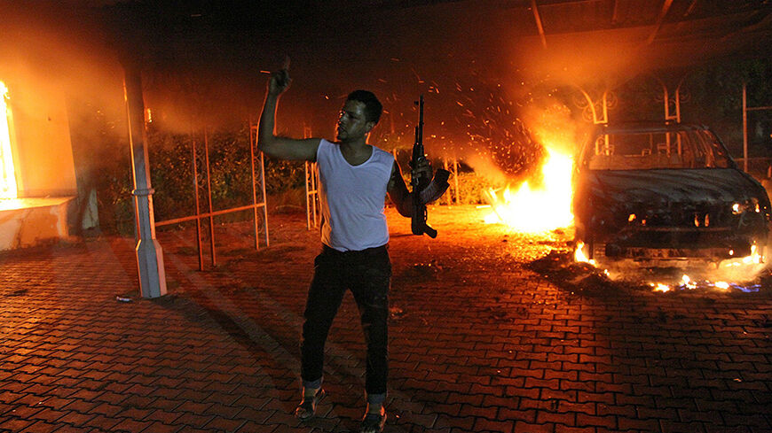 An armed man waves his rifle as buildings and cars are engulfed in flames after being set on fire inside the US consulate compound in Benghazi late on September 11, 2012. An armed mob protesting over a film they said offended Islam, attacked the US consulate in Benghazi and set fire to the building, killing one American, witnesses and officials said.          AFP PHOTO        (Photo credit should read STR/AFP/GettyImages)
