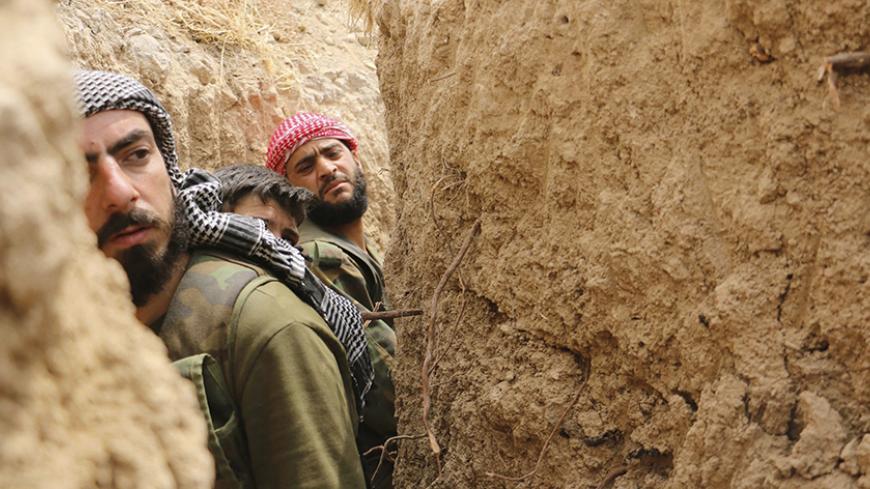 Jaysh al-Islam (Army of Islam) rebel fighters walk inside a trench at the Tal-Kurdi frontline in the Eastern Ghouta of Damascus, May 10, 2015. Jaysh al-Islam (Army of Islam) fighters said that this was an operation to take control of the highway connecting Damascus to Homs, and that they have made advances in Tal-Kurdi. REUTERS/Amer Almohibany  - RTX1CD08