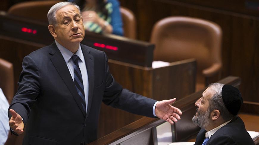 Israeli Prime Minister Benjamin Netanyahu (L) gestures as he speaks to incoming minister Aryeh Deri, party leader of the Ultra-Orthodox Shas party, in the Knesset, the Israeli parliament, in Jerusalem May 13, 2015. Netanyahu's emerging government scraped by its first parliamentary test on Wednesday, paving the way for the new cabinet to be sworn in after two months of difficult coalition building. REUTERS/Ronen Zvulun TPX IMAGES OF THE DAY - RTX1CSJH