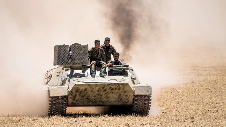 Kurdish People's Protection Units (YPG) fighters drive a tank at the eastern entrances to the town of Tal Abyad in the northern countryside of Raqqa, Syria, June 14, 2015, after they took control of nearby Suluk town from Islamic State fighters. The YPG, working with the U.S.-led alliance and small Syrian rebel groups, has pushed into Islamic State's Syrian stronghold of Raqqa province, threatening one of its supply lines to the jihadists' de facto capital, Raqqa city. REUTERS/Rodi Said - RTX1GFQ8
